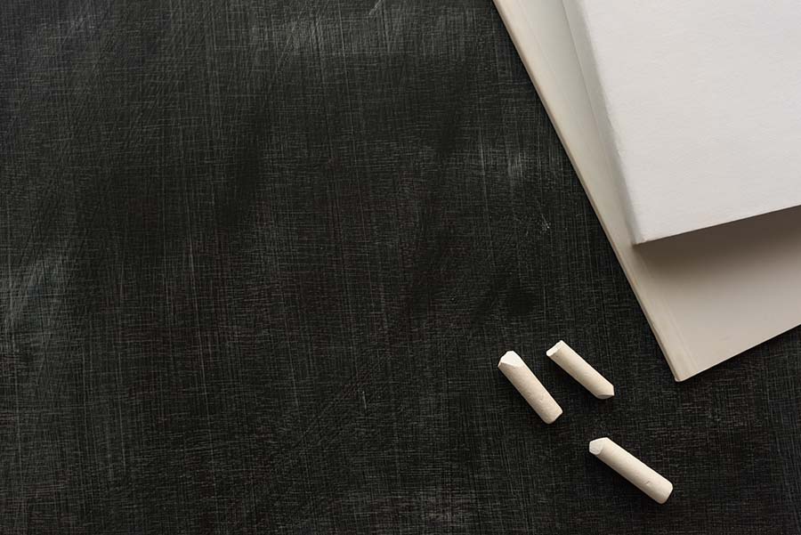 chalk board with chalk pieces and two books stacked